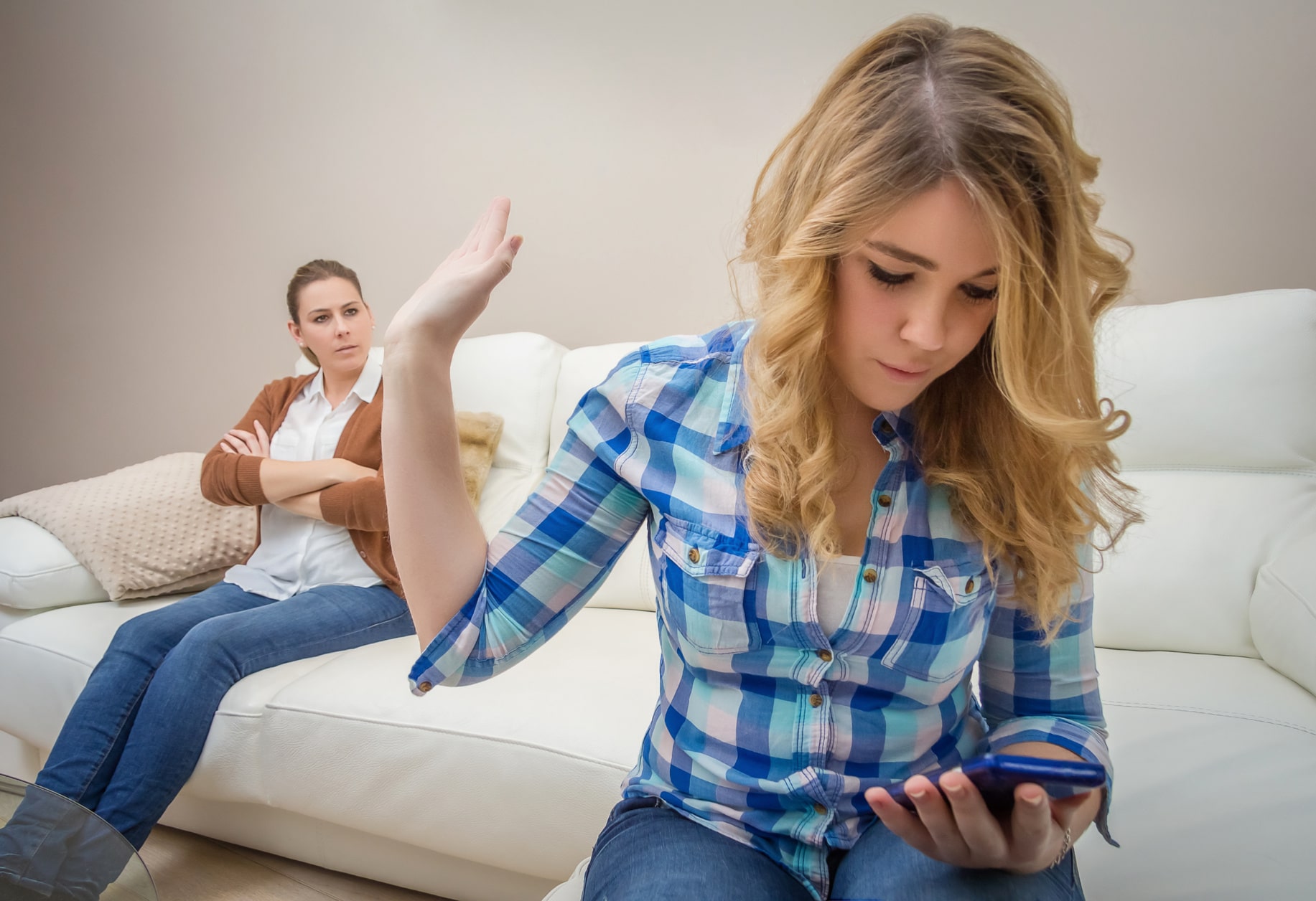 Teenage daughter looking messages in a smartphone and ignoring her furious mother. Bad family communication concept by new technologies